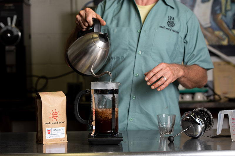 Pour water in, just off the boil on top of coffee.
