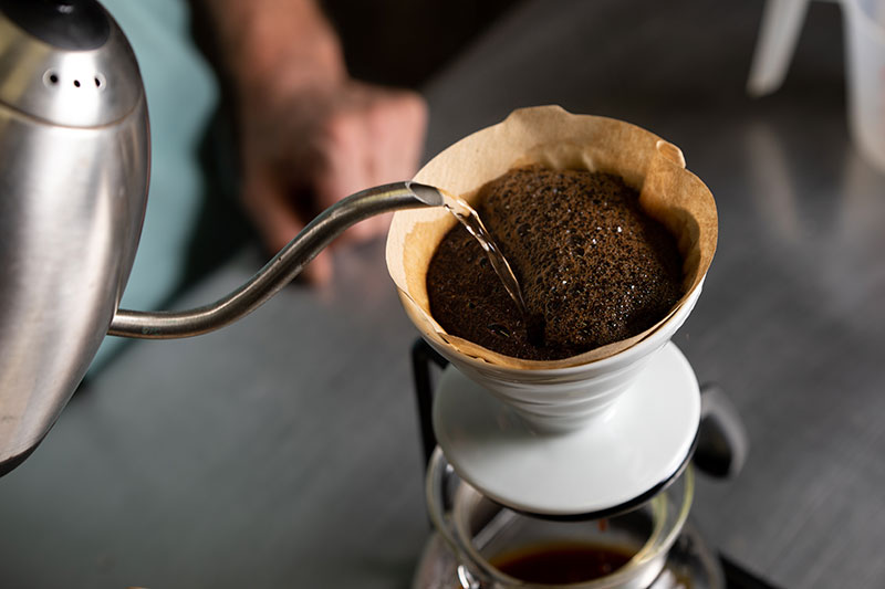 Maintain a consistent flow as you pour a minimum of five passes of water over the coffee grounds, being sure to go back and forth over the entire slurry.
